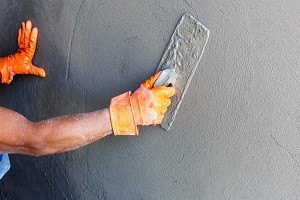 plasterer concrete worker at wall of house construction