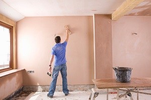 Man plastering wall in house under construction